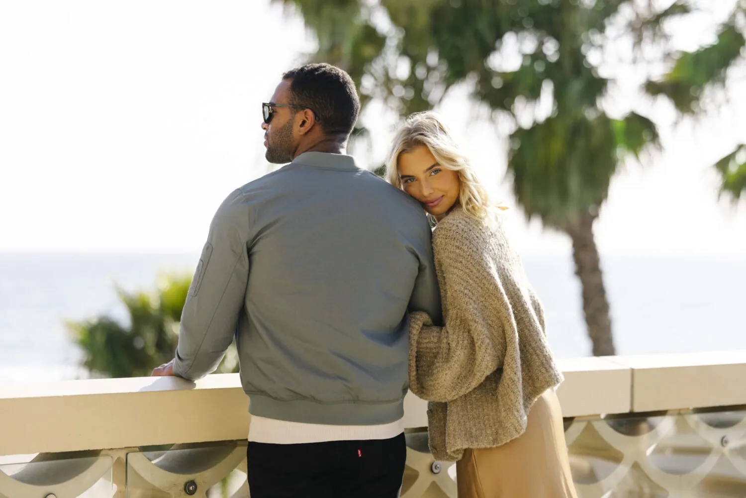 A couple enjoying the ocean view from Casa Del Mar´s terrace, with palm trees in the background.