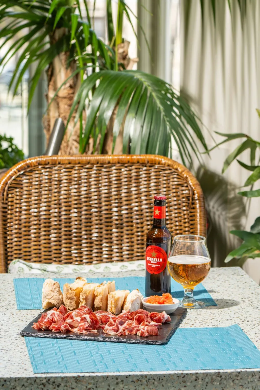 A table with cured meats, bread, a bottle of beer, a glass of beer, and a small dish of caviar.