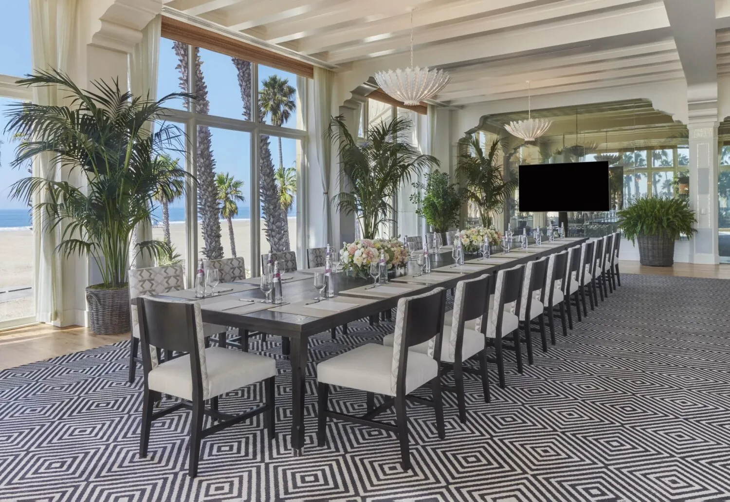 Bright event space with a long conference table and ocean views of Santa Monica beach.