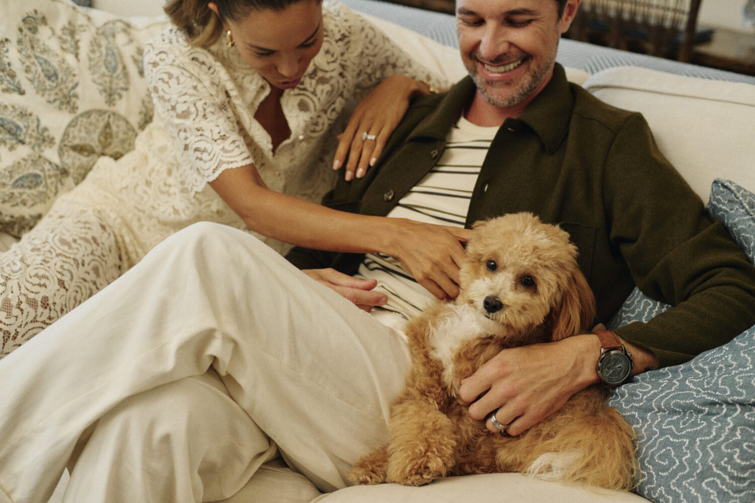 A couple sitting on the couch with their small dog in a suite at Shutters on the Beach.