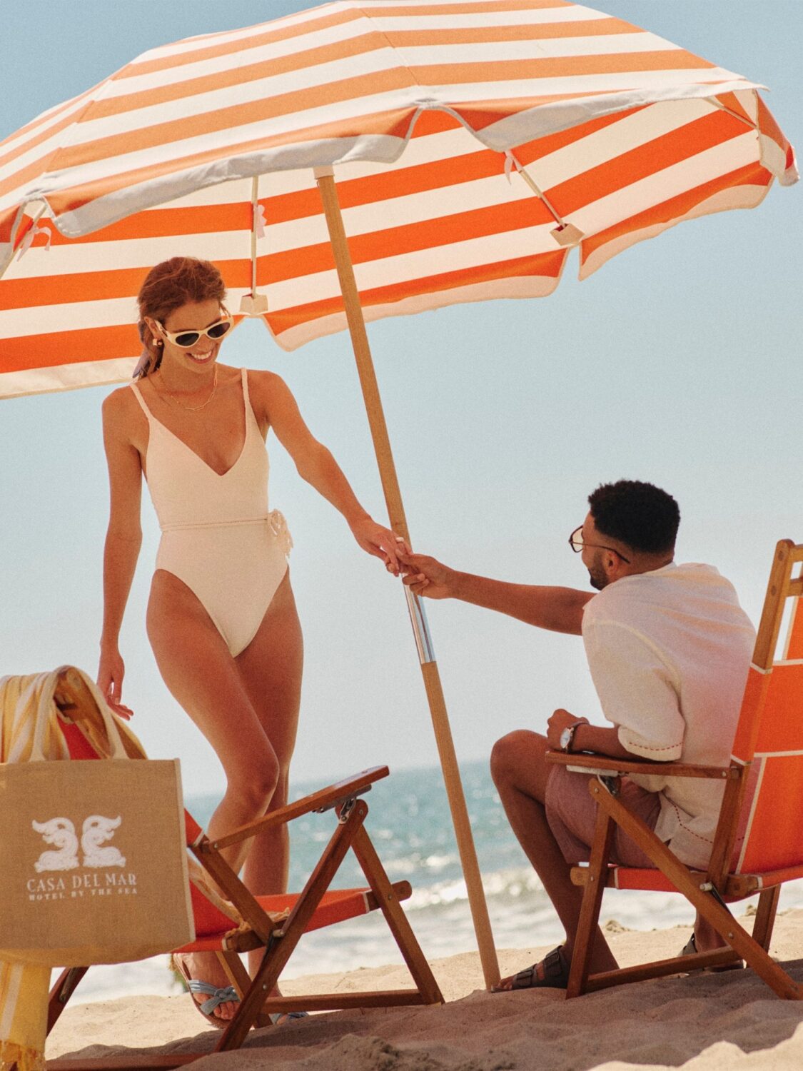 A couple holding hands at the beach under an umbrella at Hotel Casa del Mar