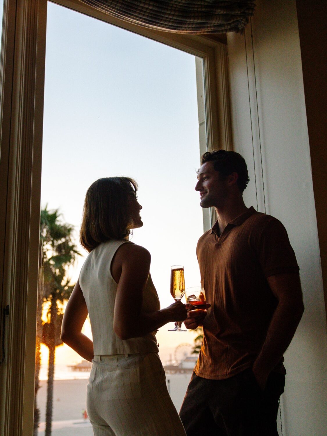 A couple looking out the window enjoying a sunset cocktail