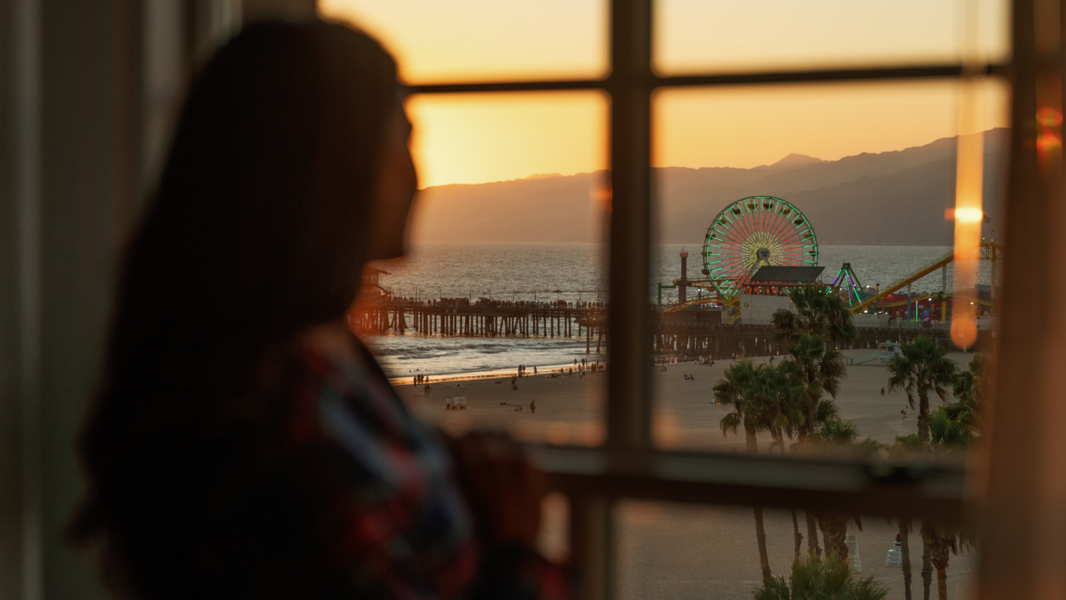 woman looking out to the santa monica pier from her arched window guest room