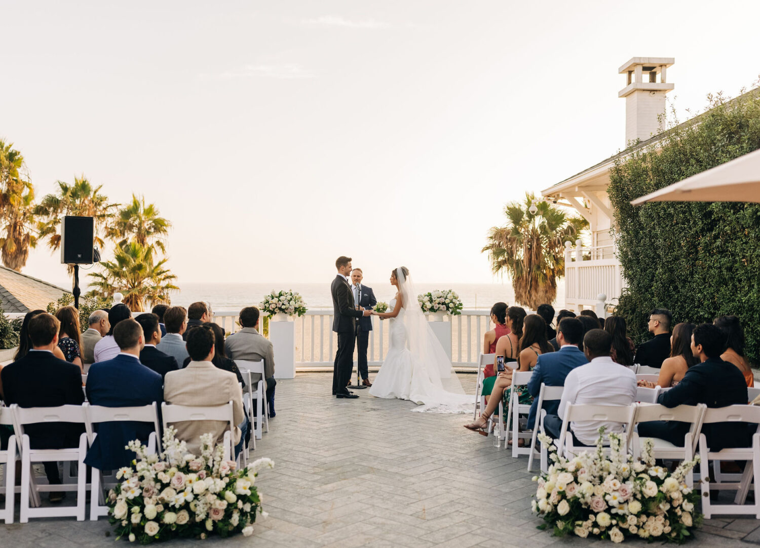 Romantic beachside wedding ceremony with a bride and groom exchanging vows at sunset.