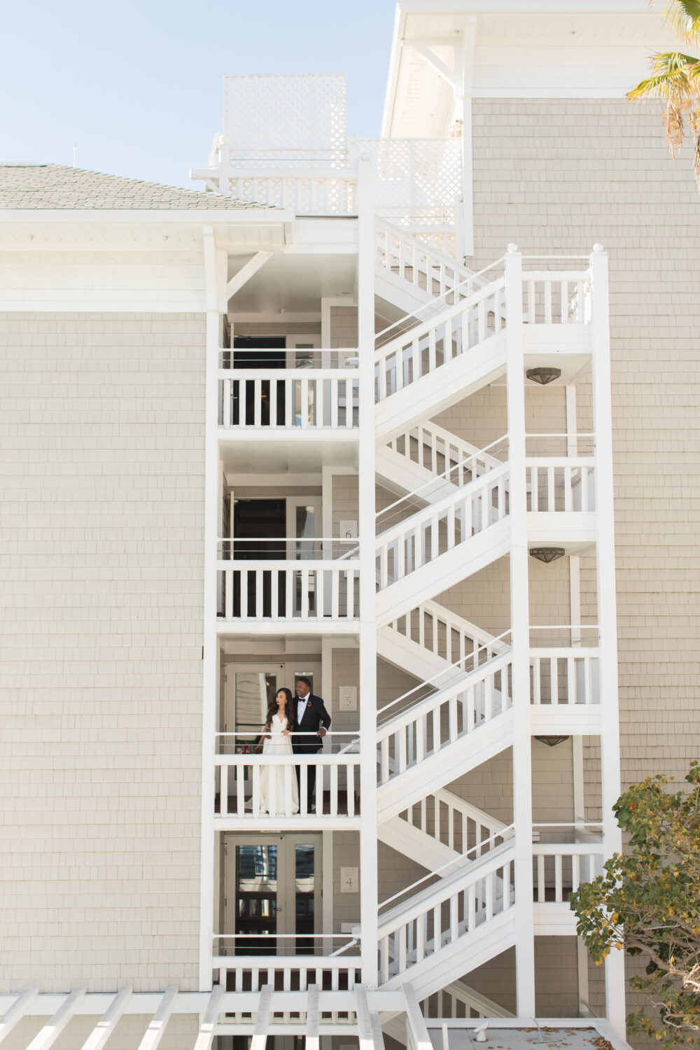 A couple in wedding attire walking down a staircase on their wedding day.