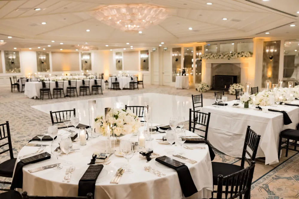 A beautifully arranged reception hall with elegant tables, candles, and floral decor.