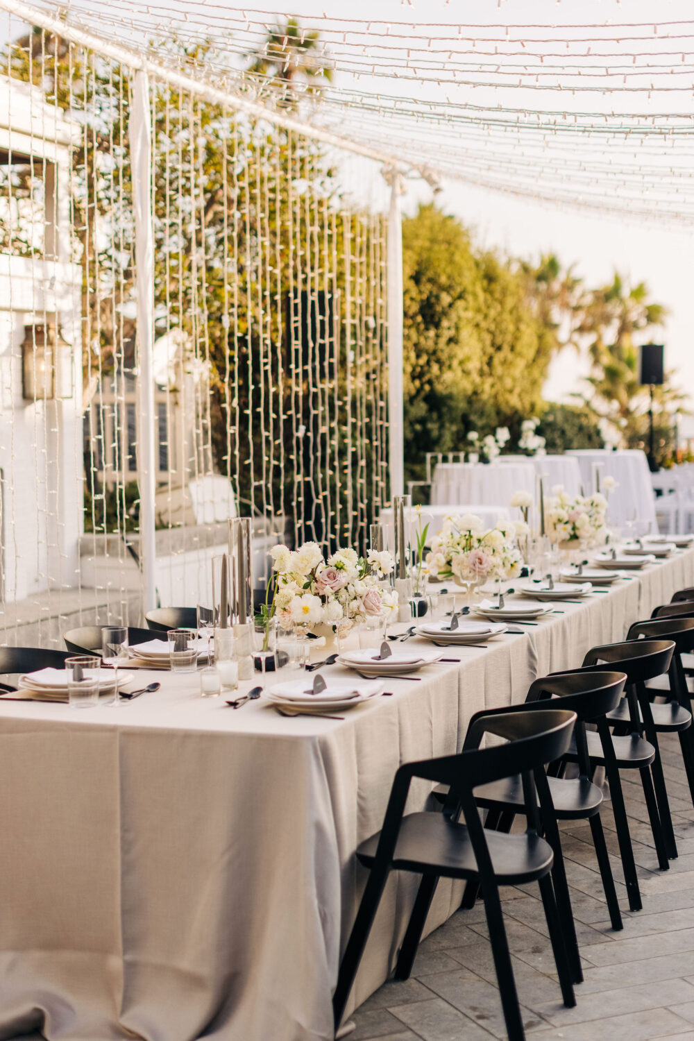 Elegant outdoor dinner with floral arrangements and string lights.