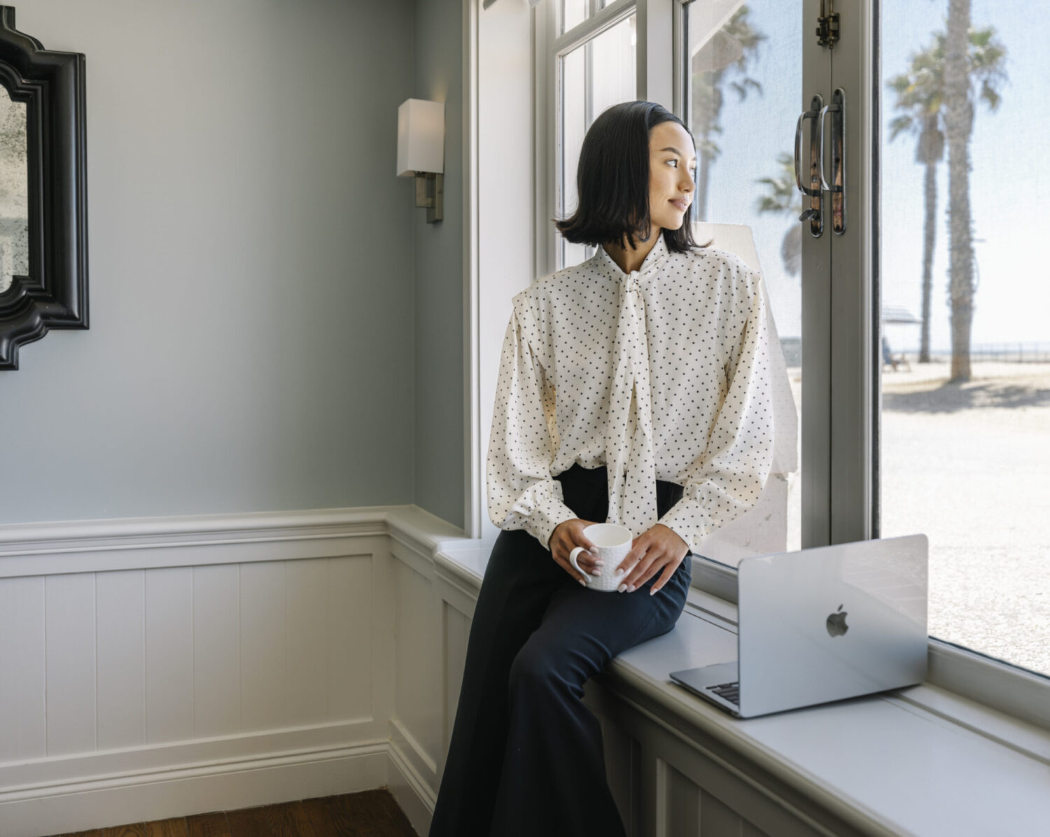 meeting expert looking out window with computer infront of her