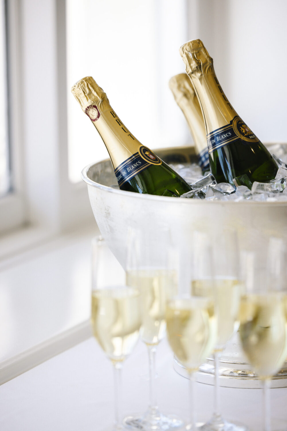 Chilled champagne bottles in an ice bucket with flutes filled, ready for celebration.