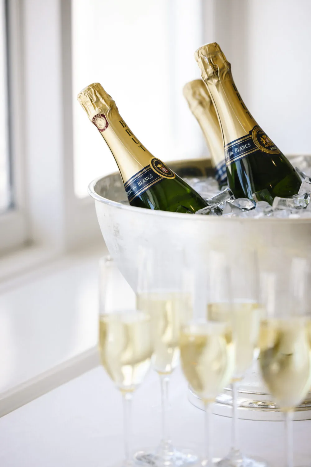 Chilled champagne bottles in an ice bucket with flutes filled, ready for celebration.