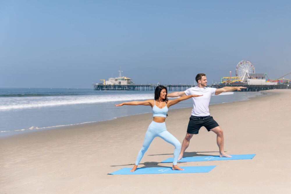 man & woman in warrior two pose on the beach