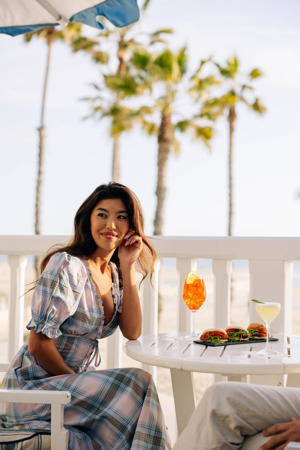 Woman enjoying seaside dining with cocktails and sliders.