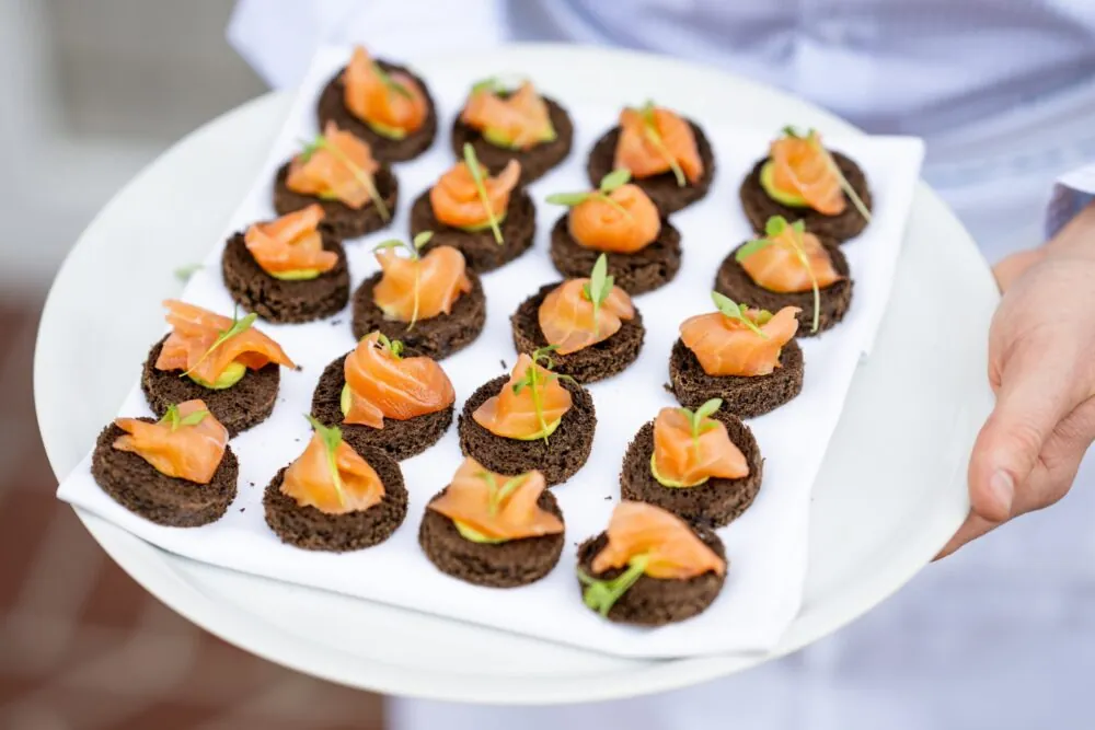 Elegant salmon canapés on dark rye bread with a garnish of microgreens.