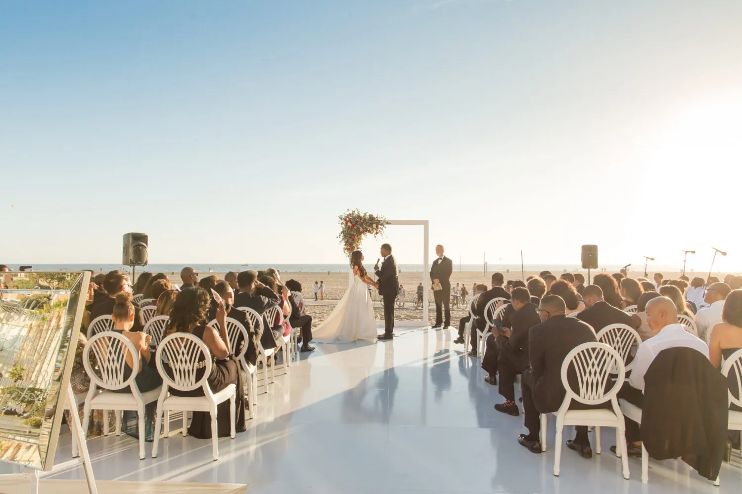 Elegant outdoor wedding with chandeliers, floral decor, and a coastal view.