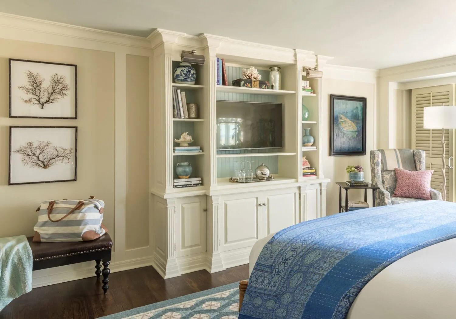 Coastal-style bedroom with built-in shelves, a TV, blue bedding, and ocean-inspired decor.