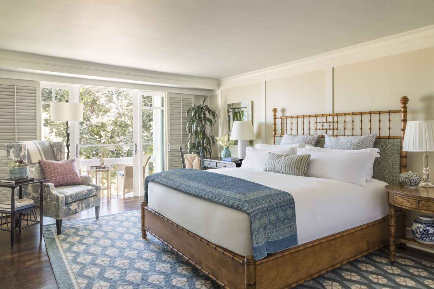 A serene bedroom with a bamboo bed, blue accents, and a private balcony with lush greenery.