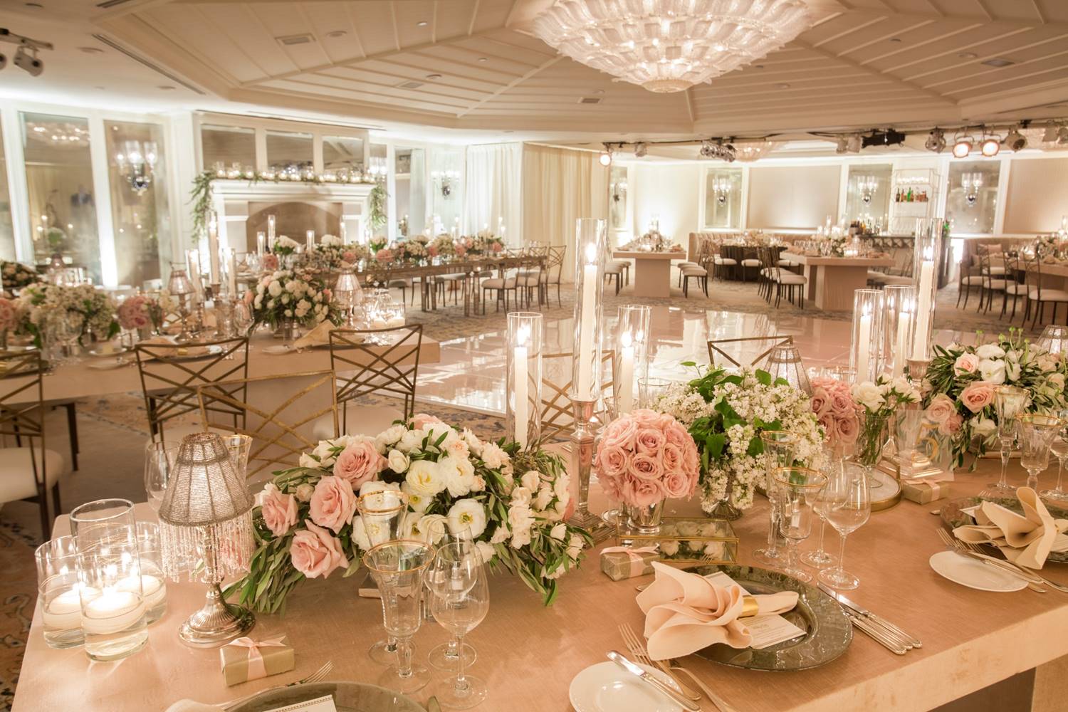 Elegant wedding reception hall with floral arrangements, candlelit tables, and a grand chandelier.