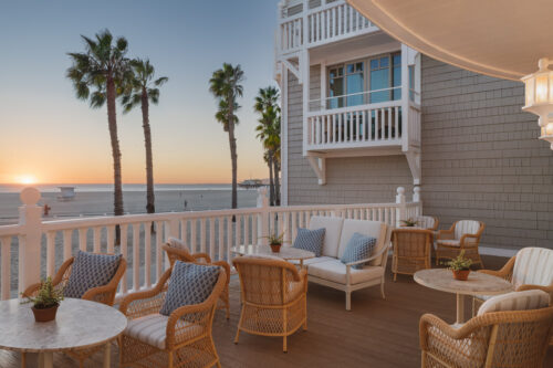 Shutters beachfront patio with wicker chairs, small tables, and a sunset view over the ocean.