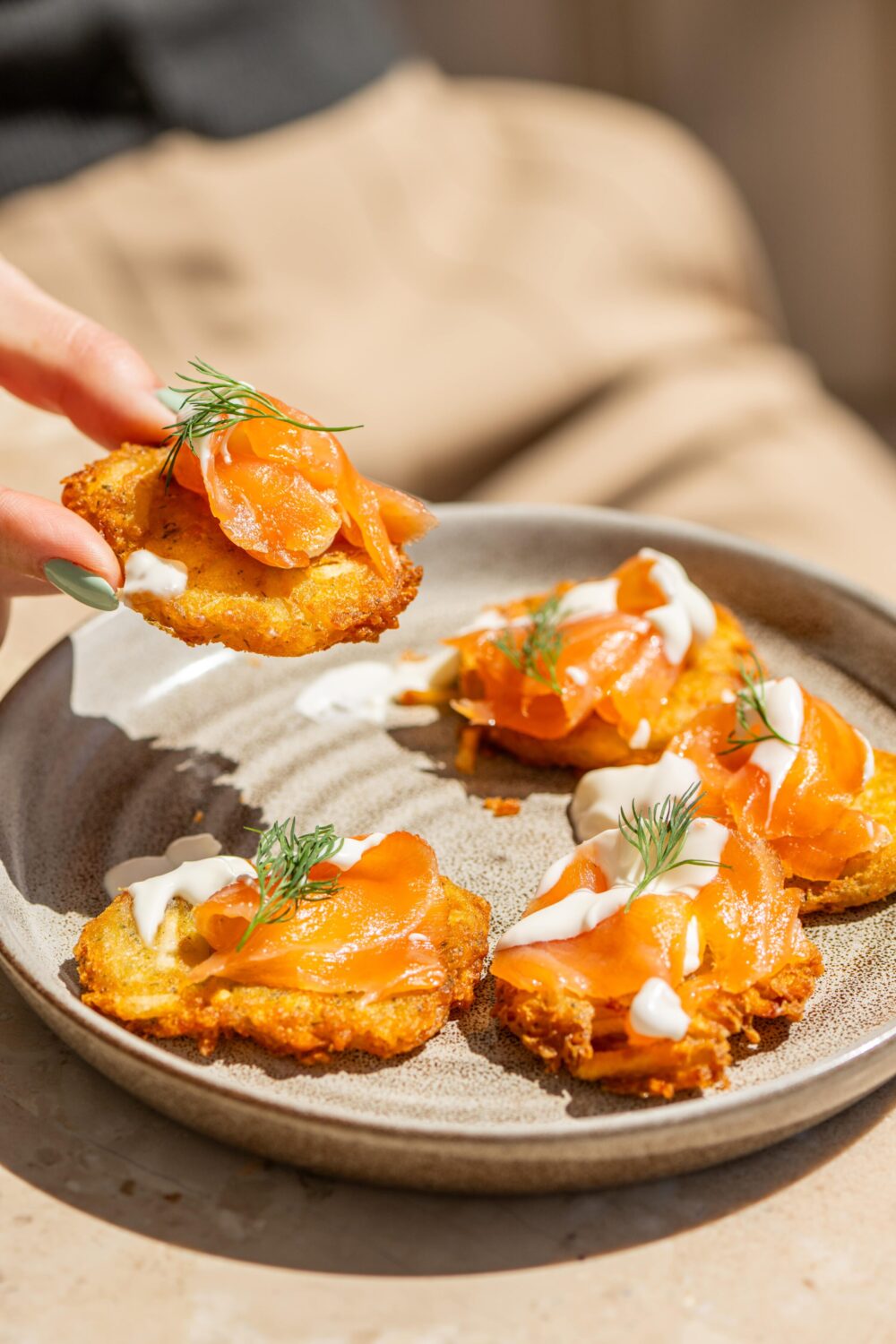 Fried appetizers topped with sour cream and dill on a plate.