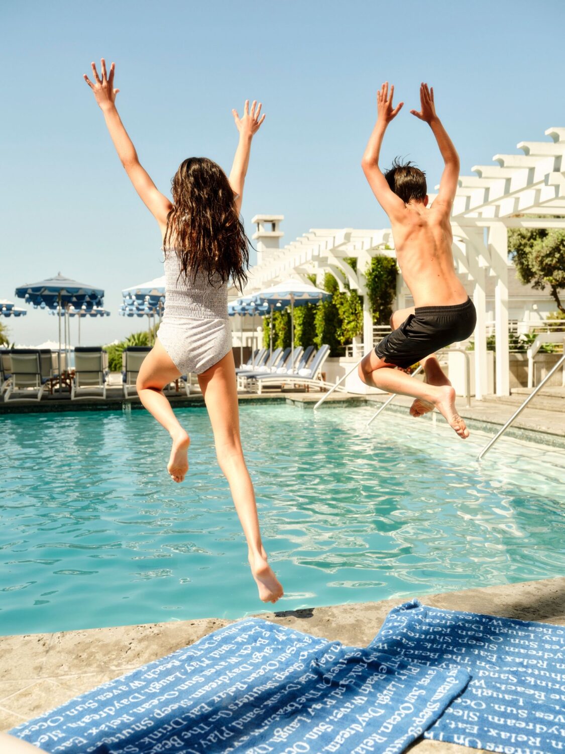 A boy and girl jumping into the pool in Santa Monica