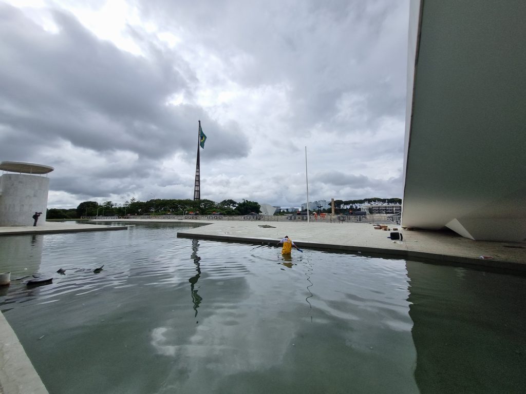 Funcionário faz a limpeza do espelho d'água do Palácio do Planalto, que ficou cheio de papéis, móveis e outros lixos atirados de dentro do prédio.