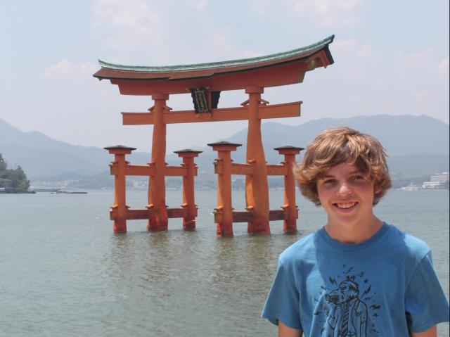 Teen poses in front of a traditional temple in Japan during their summer high school program.