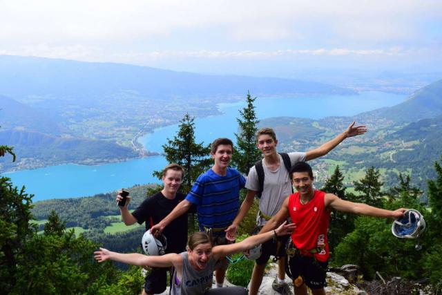 Group of happy teens on mountaintop during summer adventure program