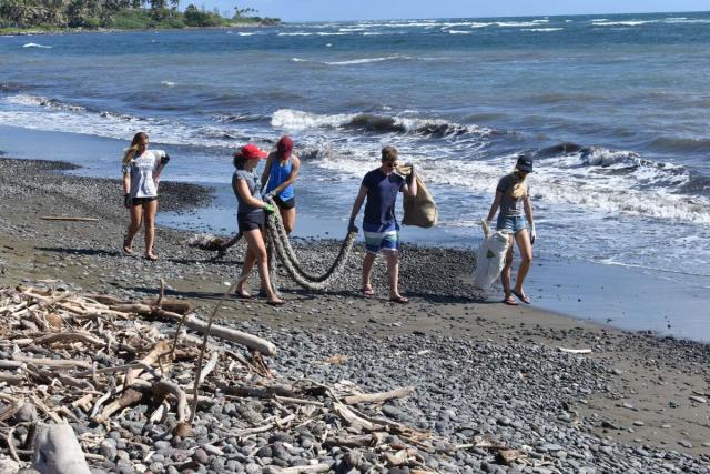 Students clean up a beach in Hawaii on their teen summer service program.