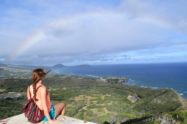 Teen girl admires rainbow on summer service program in Hawaii.
