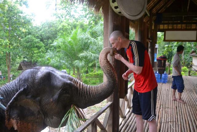 Teenage traveler kisses elephant during summer youth program in Southeast Asia