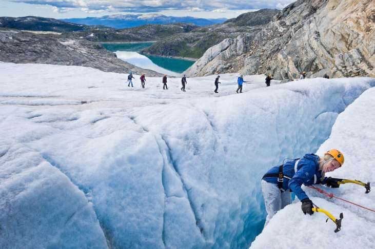 Teenage travelers climb glacier during summer youth travel program in Scandinavia