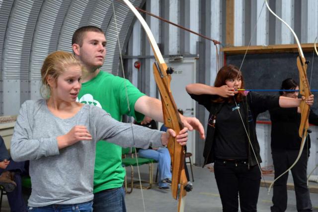Teen travelers practice archery bow and arrow during summer youth adventure travel program in Ireland
