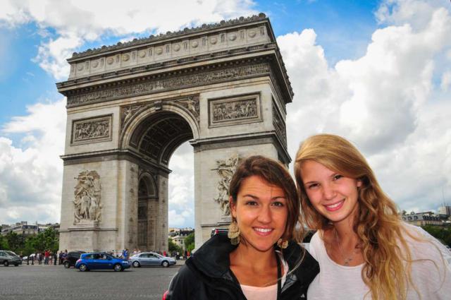 Smiling teenage travelers visit Arc de Triomphe during summer student travel program in France