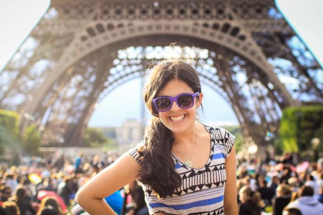 Teen traveler poses in front of Eiffel Tower on summer travel program to France