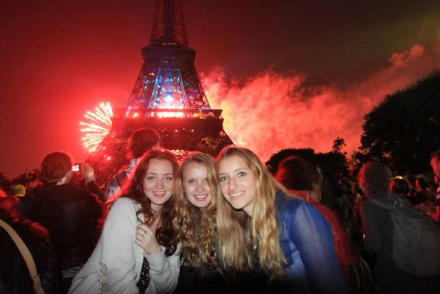 Teenage travelers watch fireworks on Champs de Mars at Eiffel Tower during summer travel adventure program