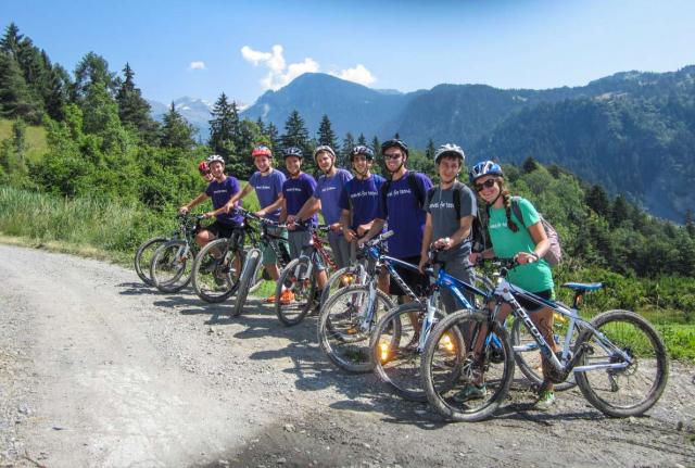 Teens bike in Alps mountains on summer youth travel program