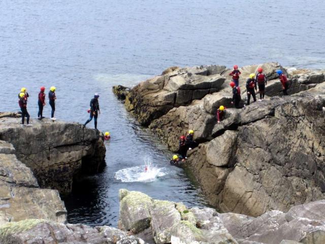 Teen travelers coasteering during summer youth adventure travel program in Ireland