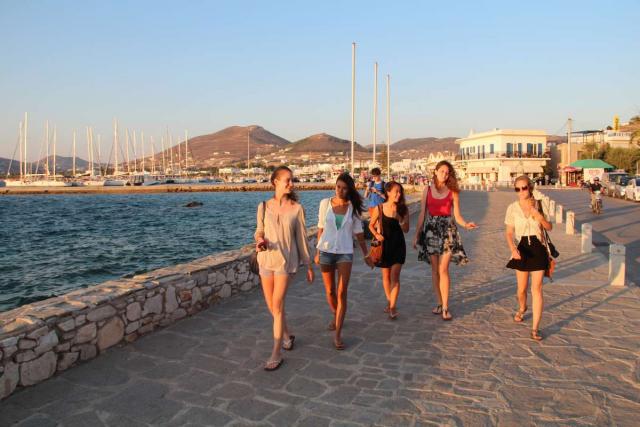 Teenage travelers walk along port boardwalk during summer youth travel program in Greece