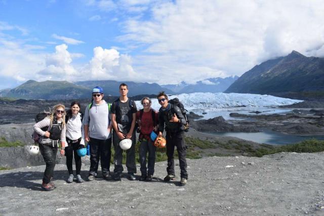 Group of happy teens hiking Alaska wilderness on travel program