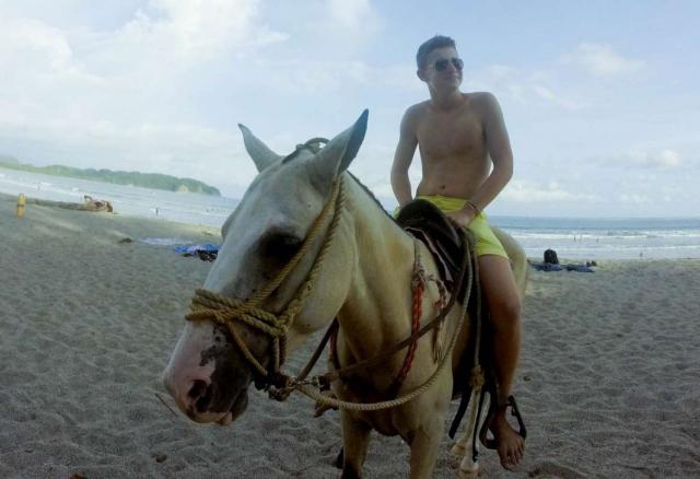 Teen rides a horse on the beach of Costa Rica on summer adventure tour.