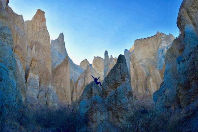 Happy teenage traveler climbs rocks during summer youth travel program in New Zealand