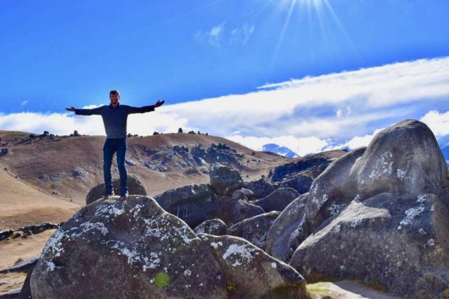 Happy teenage traveler climbs rocks during summer youth travel program in New Zealand
