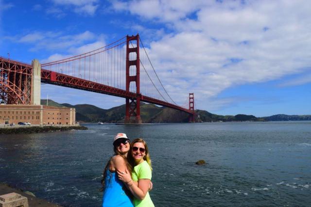 Two friends pose for a photo in front of the Golden Gate Bridge during their summer teen tour of San Francisco, California.