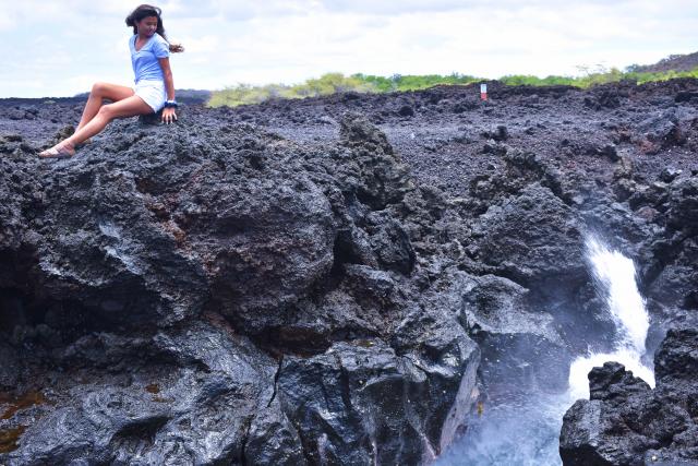 A teen admires water from atop a lava rock during summer travel program in Hawaii.