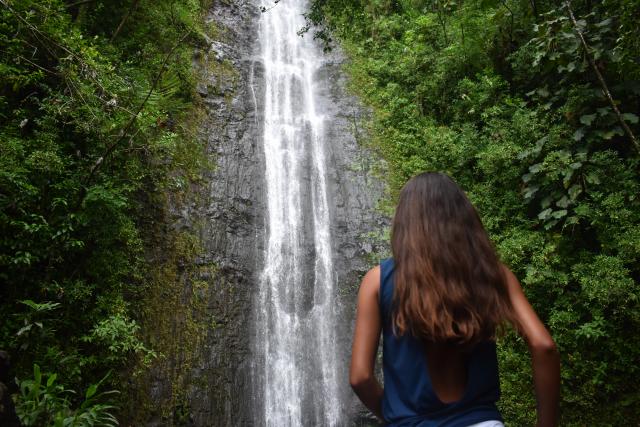 A teen admires a waterfall during their summer travel program in Hawaii.