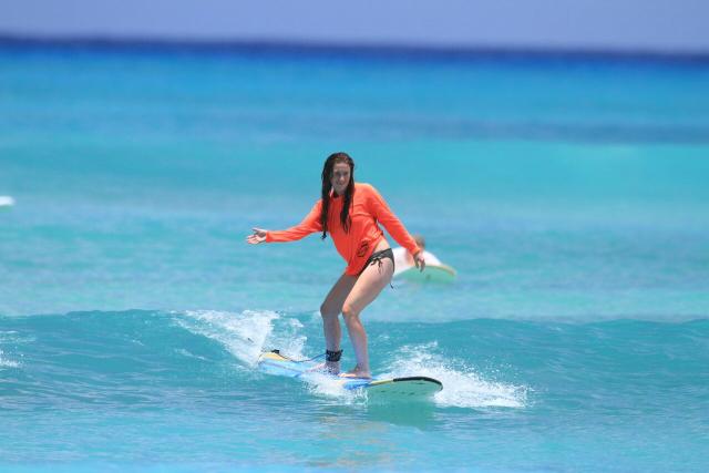 A teen learns how to surf during summer travel program in North America.