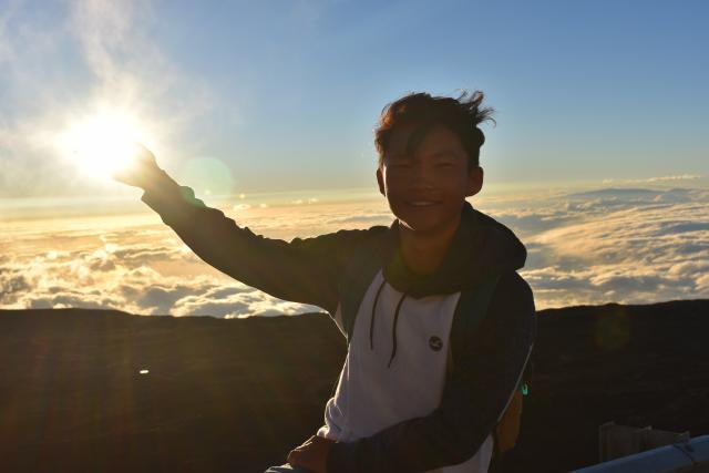 A teen catches the sunrise in Hawaii on summer travel program.