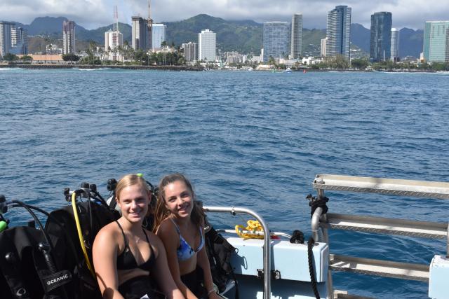 Teens pose for a photo on their boat ride past a city in Hawaii on their summer travel program.