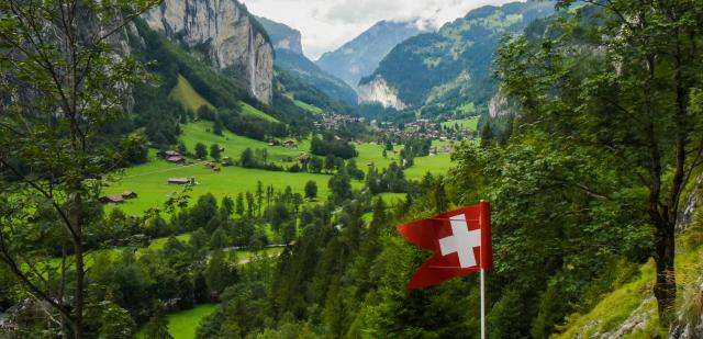 Swiss flag waving in Alpine valley seen on summer teen adventure travel program in Switzerland