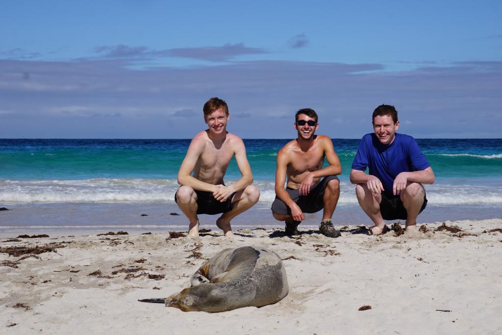 Teen travelers posing with a seal in the Galapagos Island